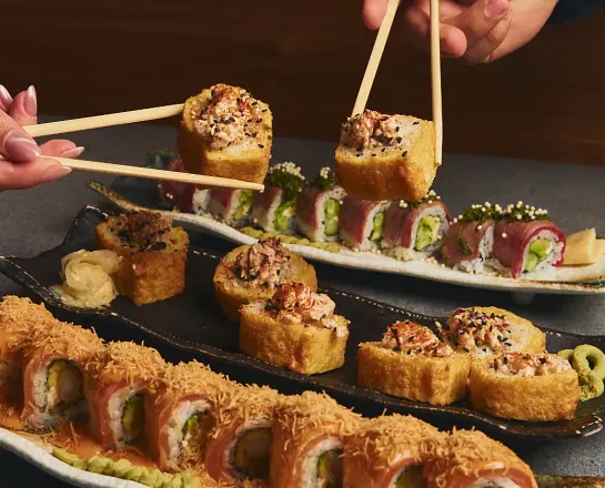 Nikkei sushi rolls arranged on a dark plate