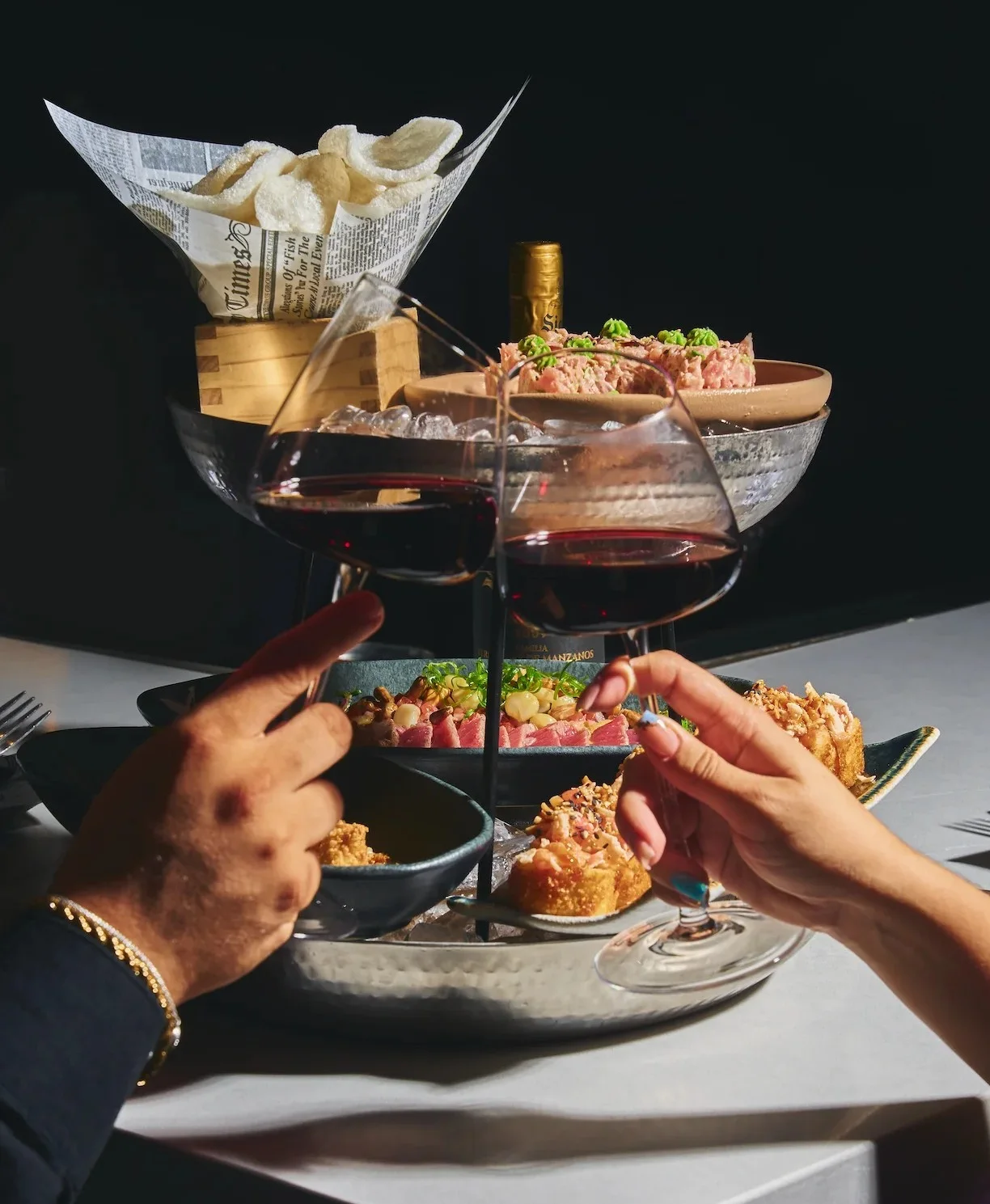 Two guests toasting red wine over a shared Peruvian tasting tower